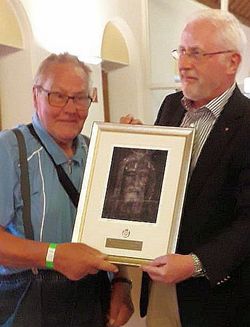 Links im Bild ist Johannes Sauerbier zu sehen sowie rechts Bern Falk. Sie halten gemeinsam das Bildes zum Dank in den Händen.